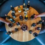 Tasting Session - person holding glass bottle on round brown wooden table