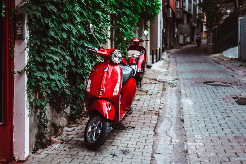 Italian Culture - red motor scooter parked beside green plants