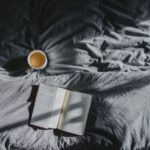 Coffee Rituals - white ceramic mug beside book on gray textile