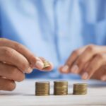 Economic Growth - a person stacking coins on top of a table