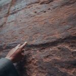 Historical Coffeehouses - a person pointing at a rock with writing on it