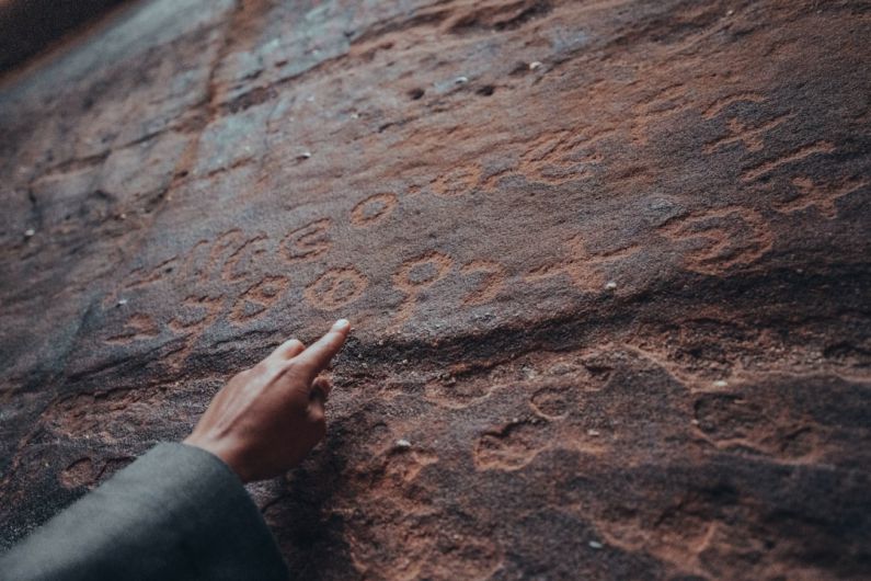 Historical Coffeehouses - a person pointing at a rock with writing on it