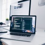 Equipment Maintenance - A MacBook with lines of code on its screen on a busy desk